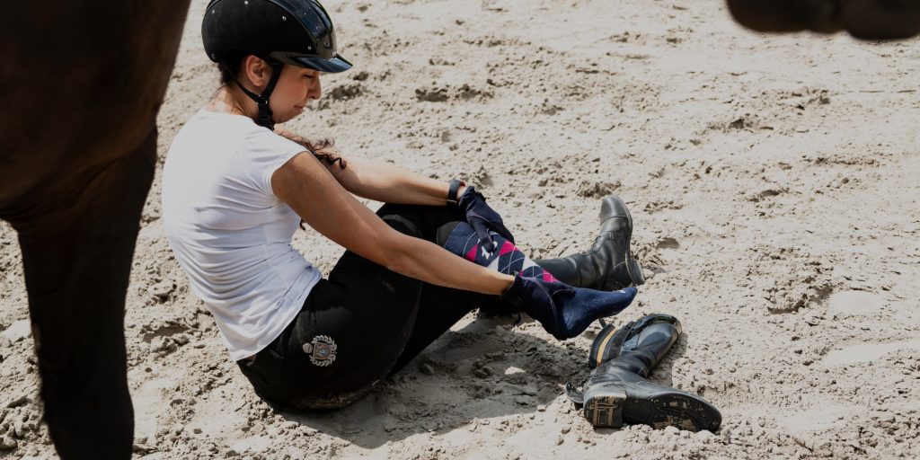 woman on ground under horse
